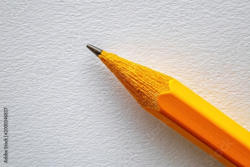 Close up of yellow pencil on smooth white paper surface