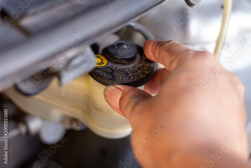 Checking brake fluid reservoir cap to ensure safe braking system performance and proper maintenance.