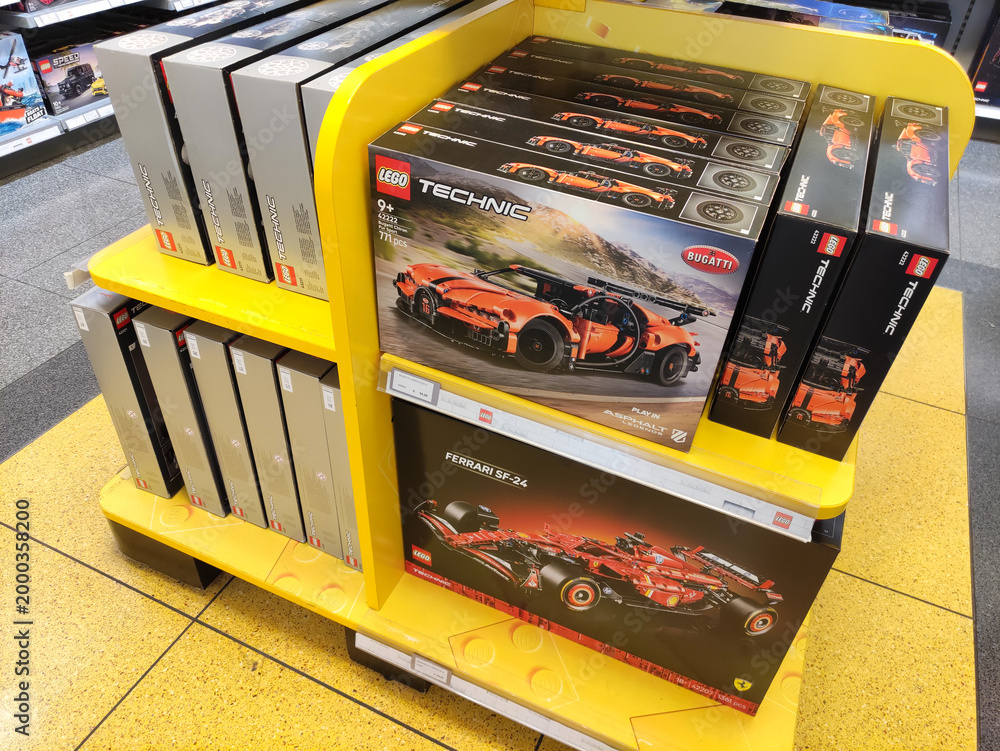 Fototapeta premium Rome, Italy - March 29, 2026: LEGO Technic Bugatti Chiron and Ferrari SF90 model kits displayed on a yellow shelf in a retail store