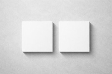 Light grey textured background with two blank square business card mockups showing subtle shadows in flat lay