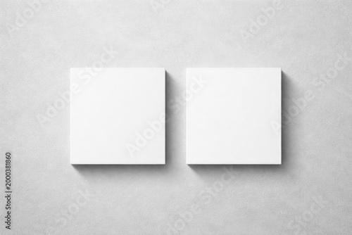 Light grey textured background with two blank square business card mockups showing subtle shadows in flat lay