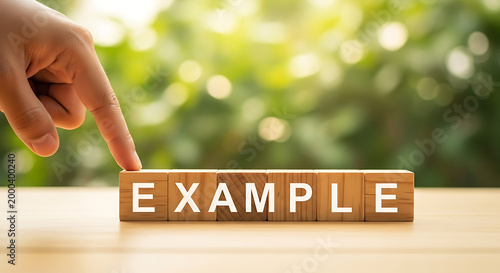 hand pressing wooden example button on blurred green nature background