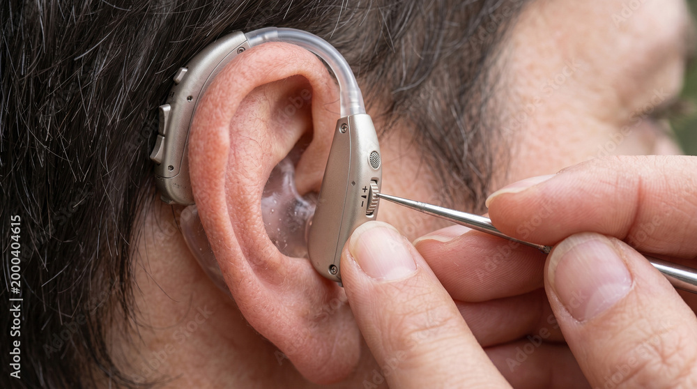 Fototapeta premium A close-up view of a doctor expertly adjusting a sleek, modern hearing aid on an elderly person