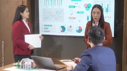 Business meeting presentation with colleagues analyzing charts on a large screen in modern conference room, discussing strategy and data trends.