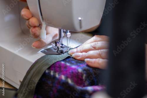 Canvastavla Close-up of hands operating a sewing machine, stitching fabric with a colorful p
