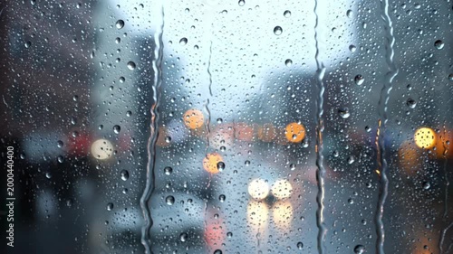 Raindrops on glass with blurred city street lights at dusk