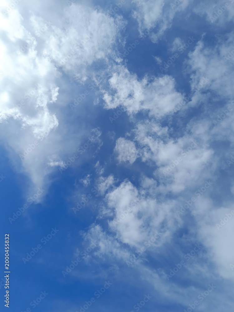 Obraz premium Blue sky filled with scattered fluffy and wispy white clouds. Bright daytime weather background
