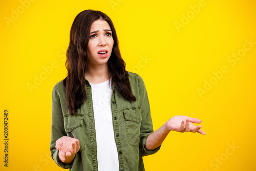 Slika na platnu Confused young woman shrugging with puzzled expression against bright yellow bac
