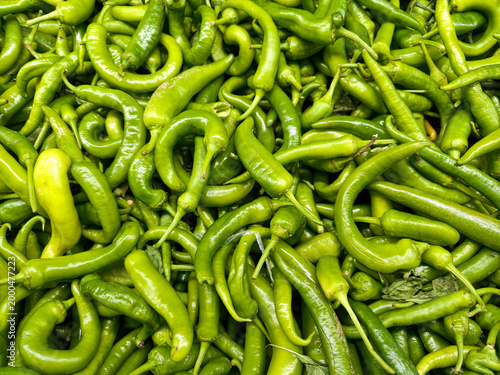 Fotografi Bright green chilies are piled together in a market setting during the day