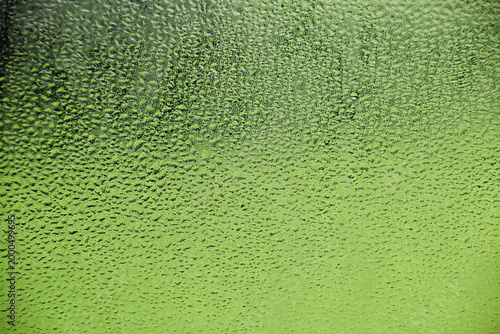 Close up view of water droplets on glass window. Abstract water droplet background in green colored tones