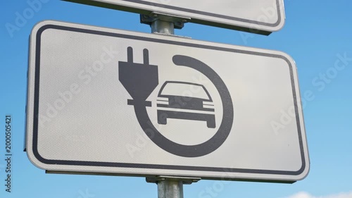 electric vehicle charging sign against bright blue sky.
