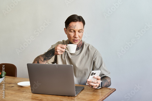 Photos Young man enjoying a quiet moment at home while sipping coffee and checking his