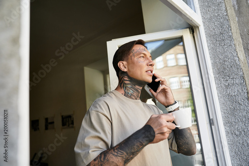Картината върху платно Charming young man enjoys a moment of blissful solitude at home while talking on