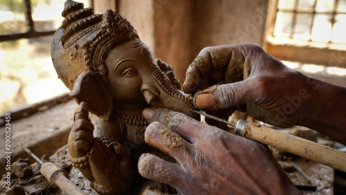 Artisan craftsman sculpting ganesha idol in intimate workshop with natural light