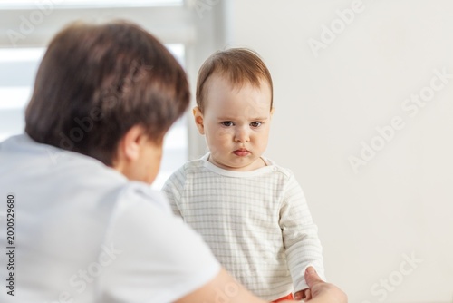 Serious toddler looking at grandmother, emotional expression and child behavior concept