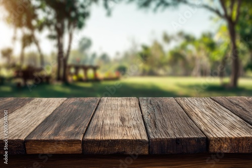 A rustic wooden surface sits in focus against a blurred background of a lush park with trees and picnic tables, creating a serene and inviting scene.