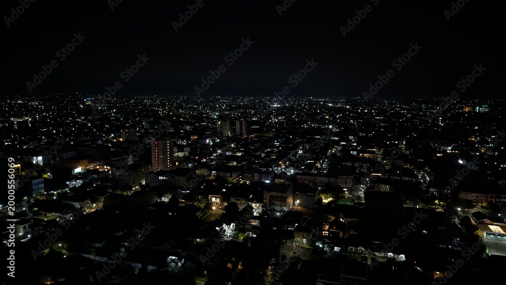 Obraz premium A nighttime view of the city, with a pitch-black sky illuminated by the lights of the surrounding houses.