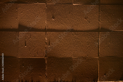 Close up of brown textured concrete wall showing geometric block pattern and rough surface. Supporting construction, architecture, renovation, urban background, copy space use
