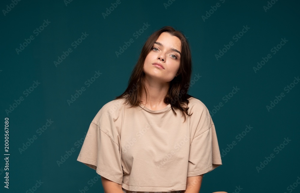 Fototapeta premium Young woman with natural beauty looking at camera against teal background expressing confidence and casual style