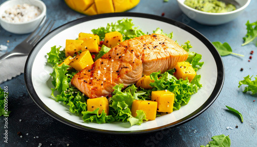 Grilled salmon and mango salad with avocado and fresh green lettuce