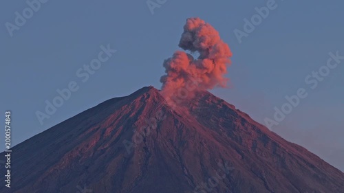 Semeru volcano erupting with a red ash cloud at sunset