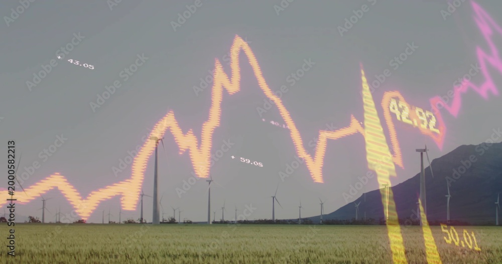 Fototapeta premium Framing wind turbines spinning over field with mountain ridge, showing glowing stock chart numbers