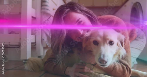 Fototapeta samoprzylepna Hugging adult woman cuddling golden dog on tiled kitchen floor, rust sweater and pink lens flare