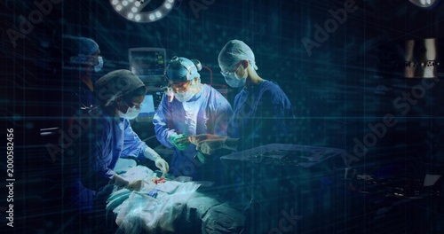 Performing surgery, surgical team in scrubs handling instrument tray and monitoring vitals in OR