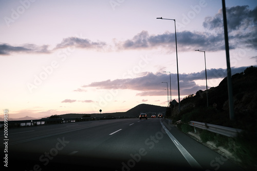 Driving on a coastal highway at dusk with streetlights illuminating the road