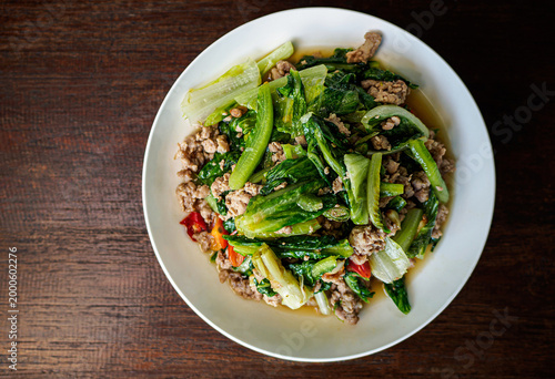 Fotografie Stir-fried cabbage vegetables with minced pork, thai food on rustic wooden table