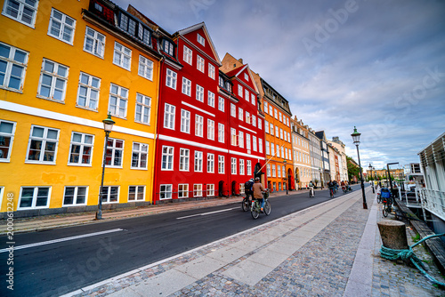 Photography People ride bicycles on colorful street in Danish city Copenhagen in the morning, Denmark, Nyhavn, Indre By district