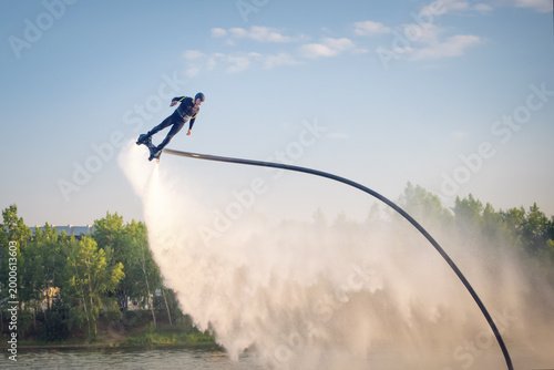 Canvas Print Flyboarding adventure over calm waters during sunset showcases thrilling aerial stunts against a serene backdrop