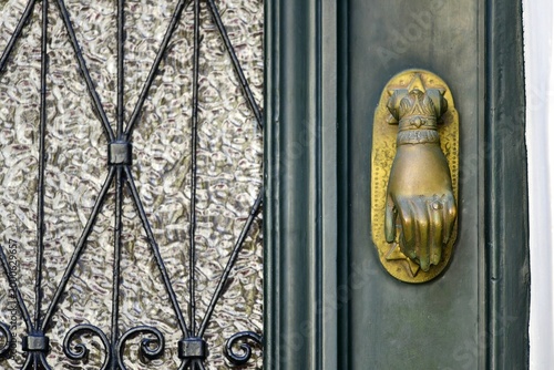 Old Neoclassical house wooden entrance door with an antique brass knocker and handcrafted wrought iron grilles.