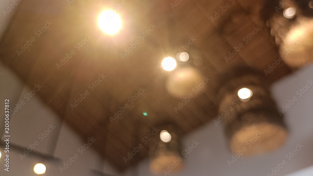 Fototapeta premium Blurred image of lights on a wooden ceiling in a room