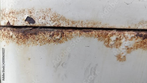 Photos A close-up photo of rusty corrosion on a worn metal surface with visible oxidation and decay marks