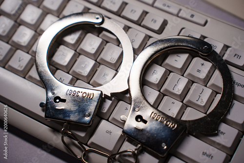 Handcuffs on computer keyboard, cybercrime and security concept