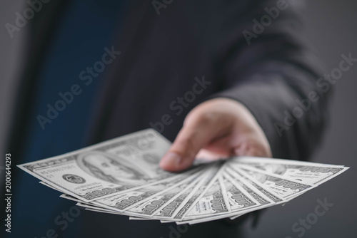 Billede på lærred Businessman handing over US dollar banknotes representing cash payment, financial transaction, investment capital, money exchange, business funding and wealth management concept in modern economy