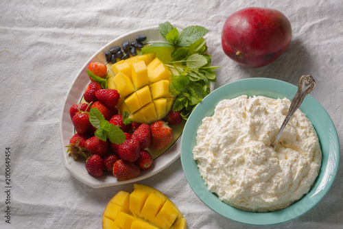 Tableau sur toile Fresh fruits with homemade cottage cheese on light textile background