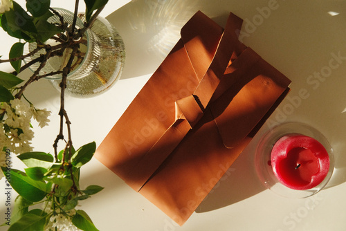 Gift bag and candle scene with a plant and vase, a warm still life for home decor and intimate moments, soft light, subtle textures and cozy atmosphere