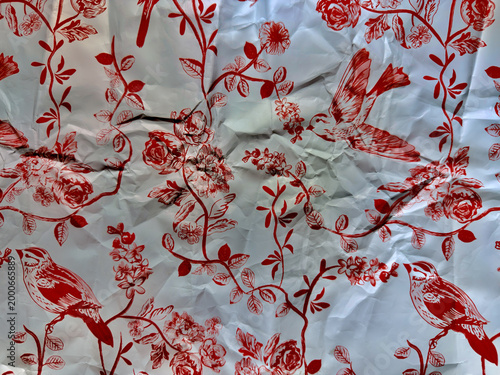 crumpled red birds perching on rose vines floral pattern wrinkled white foil texture background