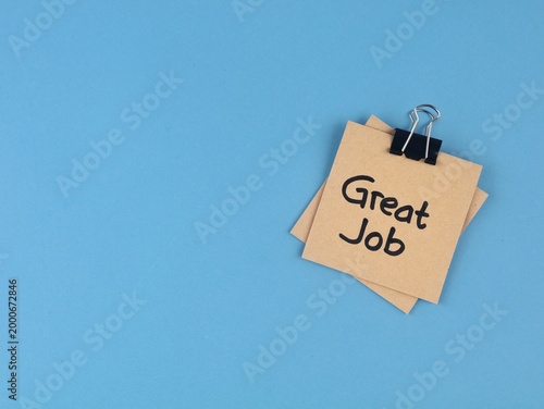 Great job message on adhesive notes with binder clip on blue background. Represents employee recognition, positive feedback, success, and professional appreciation in a workplace or educational settin
