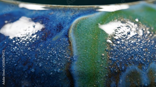 Closeup of vibrant blue and green glaze with bubbling texture on ceramic.