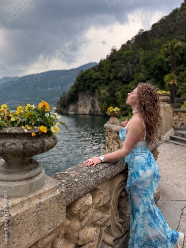 young woman in blue dress in Italy on bridge in April near mountains