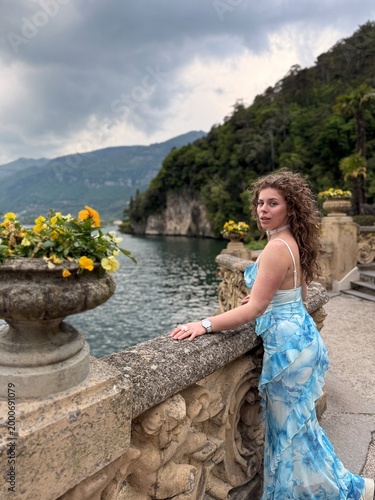 young woman in blue dress in Italy on bridge in April near mountains