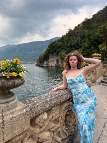 young woman in blue dress in Italy on bridge in April near mountains