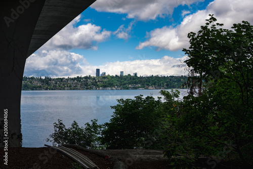 2025-05-28 VIEW OF THE SEATTLE SKYLINE FROM MERCER ISLAND UNDER THE I-90 FLOATING BRIDGE WITH A CALM LAKE WASHINGTON AND NICE CLOUD FILLED SKY