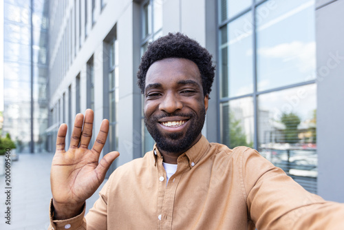 Billede på lærred Smiling man with a groomed beard and textured hair happily waving a hand, taking