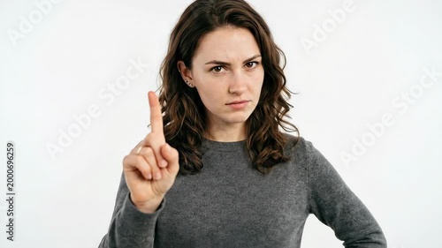 A young woman facing forward and shaking her index finger to say no, expressive posture, clean white background, soft studio lighting, confident assertive mood, ultra-realistic, no logos.