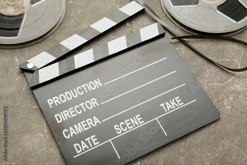Movie clapper with popcorn and film reels on grey background. Space for text