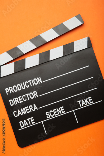 One movie clapper on orange background. Film industry. Vertical photo